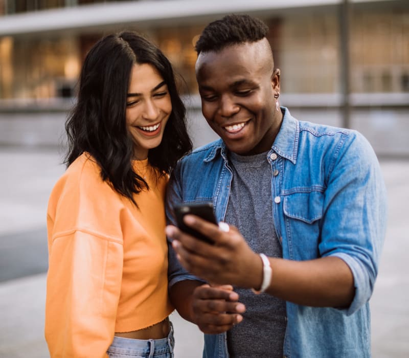 Residents smiling while viewing smartphone near The Esplanade in Lake Balboa, California