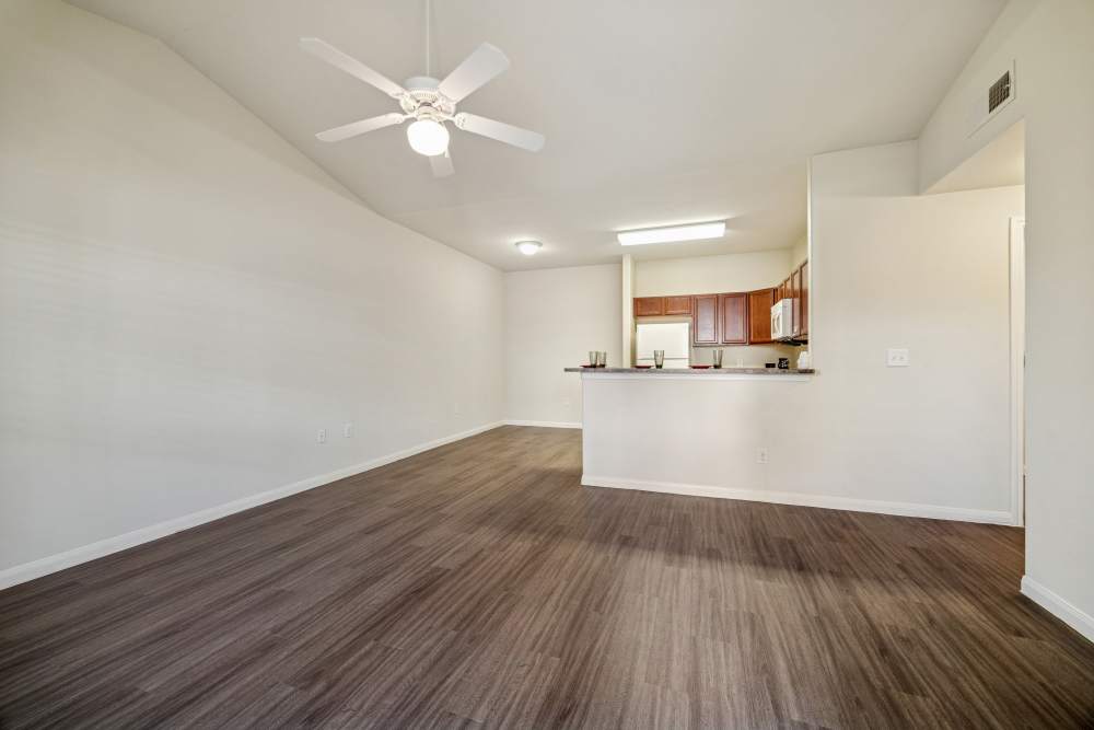Spacious living area with a modern kitchen and sleek wood flooring at Arbor Pines in Orange, Texas.