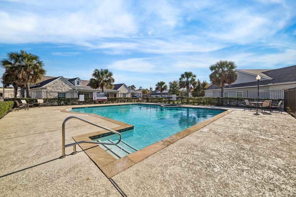 Sparkling water pool surrounded by lush landscaping at Arbor Pines in Orange, Texas.