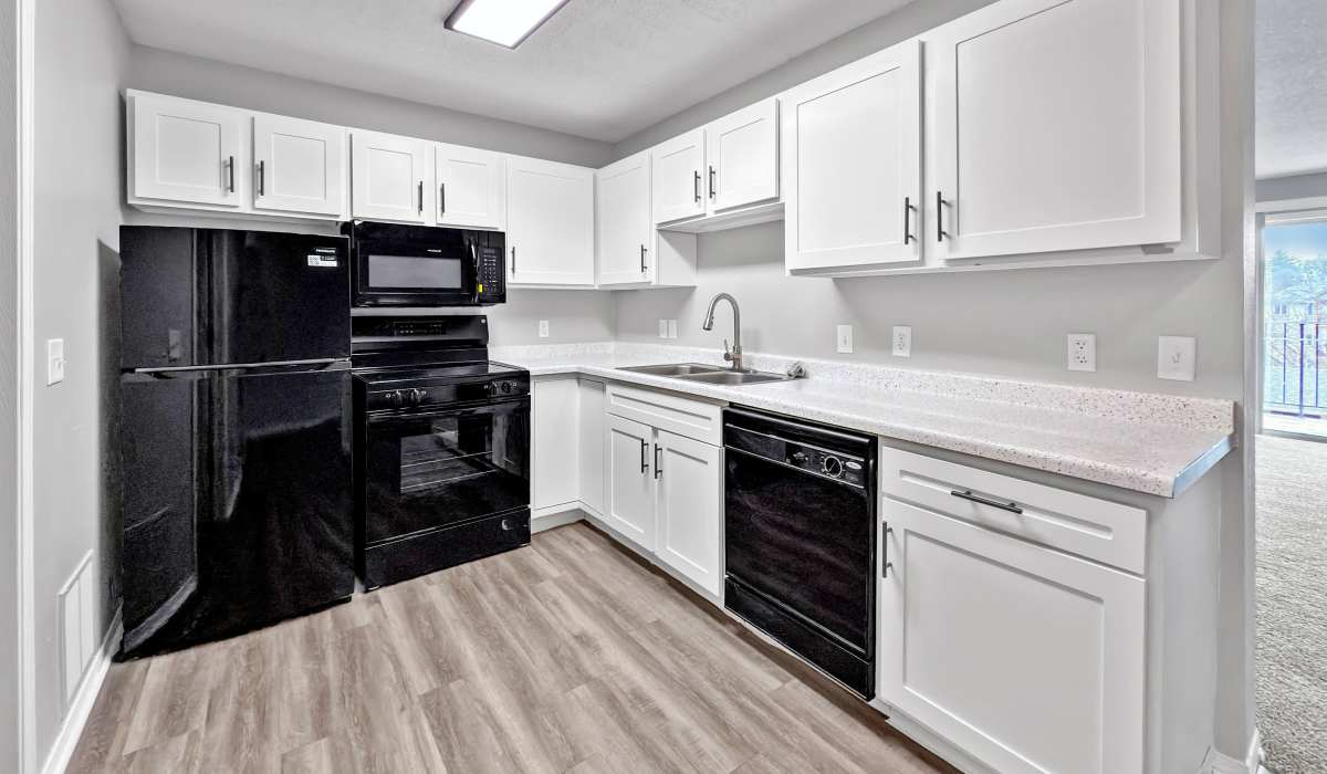 Modern kitchen with white cabinets and black appliances at Cambridge Court Apartments in West Des Moines, Iowa