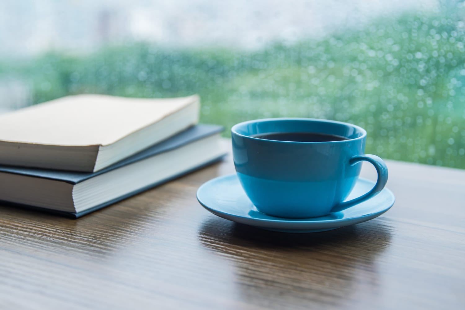 A cup of coffee and books on a table near a window at Farmington Square Tualatin in Tualatin, Oregon