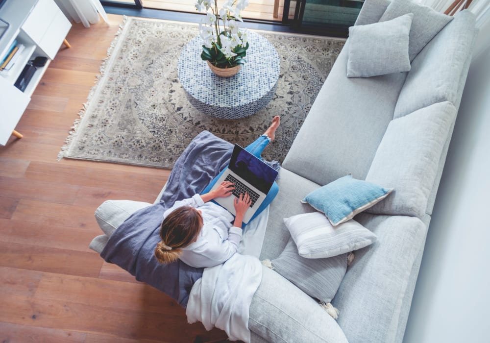 Woman relaxing on the couch browsing the web on her computer at Parkside Manor in Ewing, New Jersey