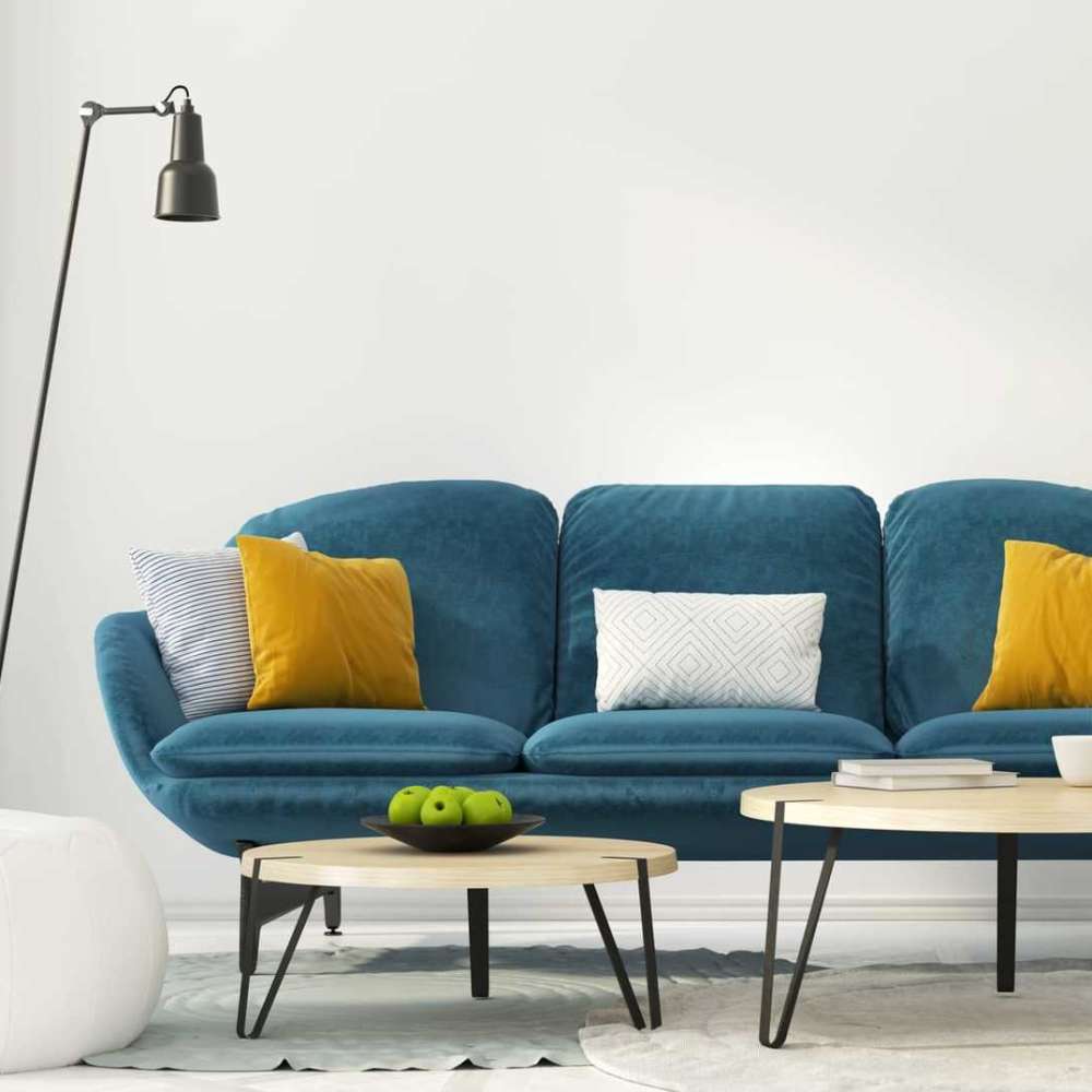 Bright living room with a blue couch, decorative pillows, and wooden coffee tables with green apples at 43 North Apartments in Grand Haven, Michigan