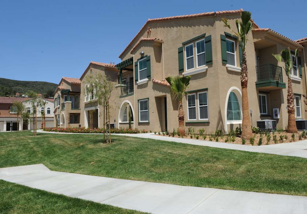 Charming two-story townhomes surrounded by lush landscaping and a tranquil walkway, perfect for modern living at Cresta Bella in San Diego, California