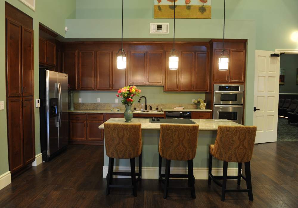 Sleek modern kitchen with rich wooden cabinetry, granite countertops, and stylish bar seating adorned with elegant floral accents, perfect for entertaining at Cresta Bella in San Diego, California