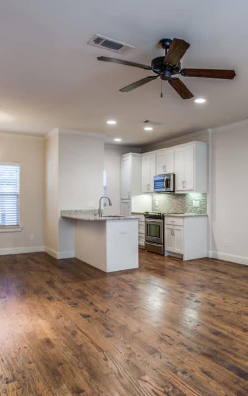 Open concept floor plan of living room with fireplace and kitchen with stainless steel appliances at The Collection Townhomes in Dallas, Texas