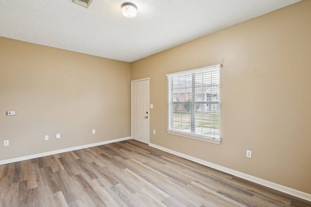 Unfurnished living room with wood-style flooring and large window at Camden Park in Canton, Mississippi