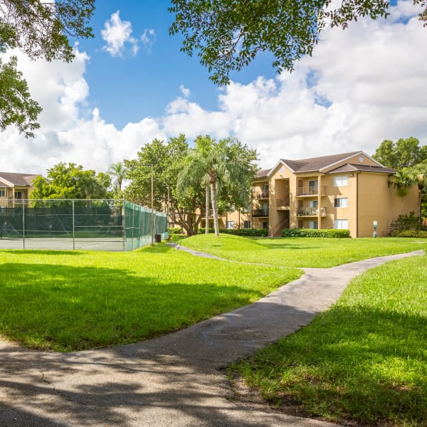 Tennis court surrounded by lush landscaping at Palmetto Place Apartments in Miami, Florida