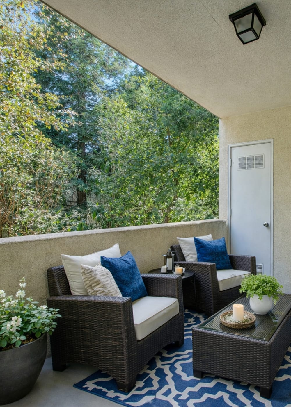 Cozy balcony with two chairs, decorative pillows, small table, and greenery in a serene setting at Westwood Bluffs in Fresno, California