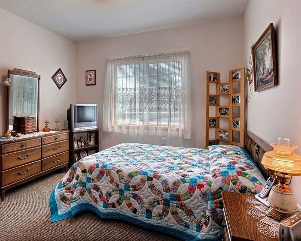 Cozy bedroom with dresser and side table at Milestone Senior Living Hillsboro in Hillsboro, Wisconsin.