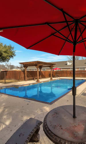 Swimming pool and patio table with umbrella at Summit Point Apartments in Mesquite, Texas