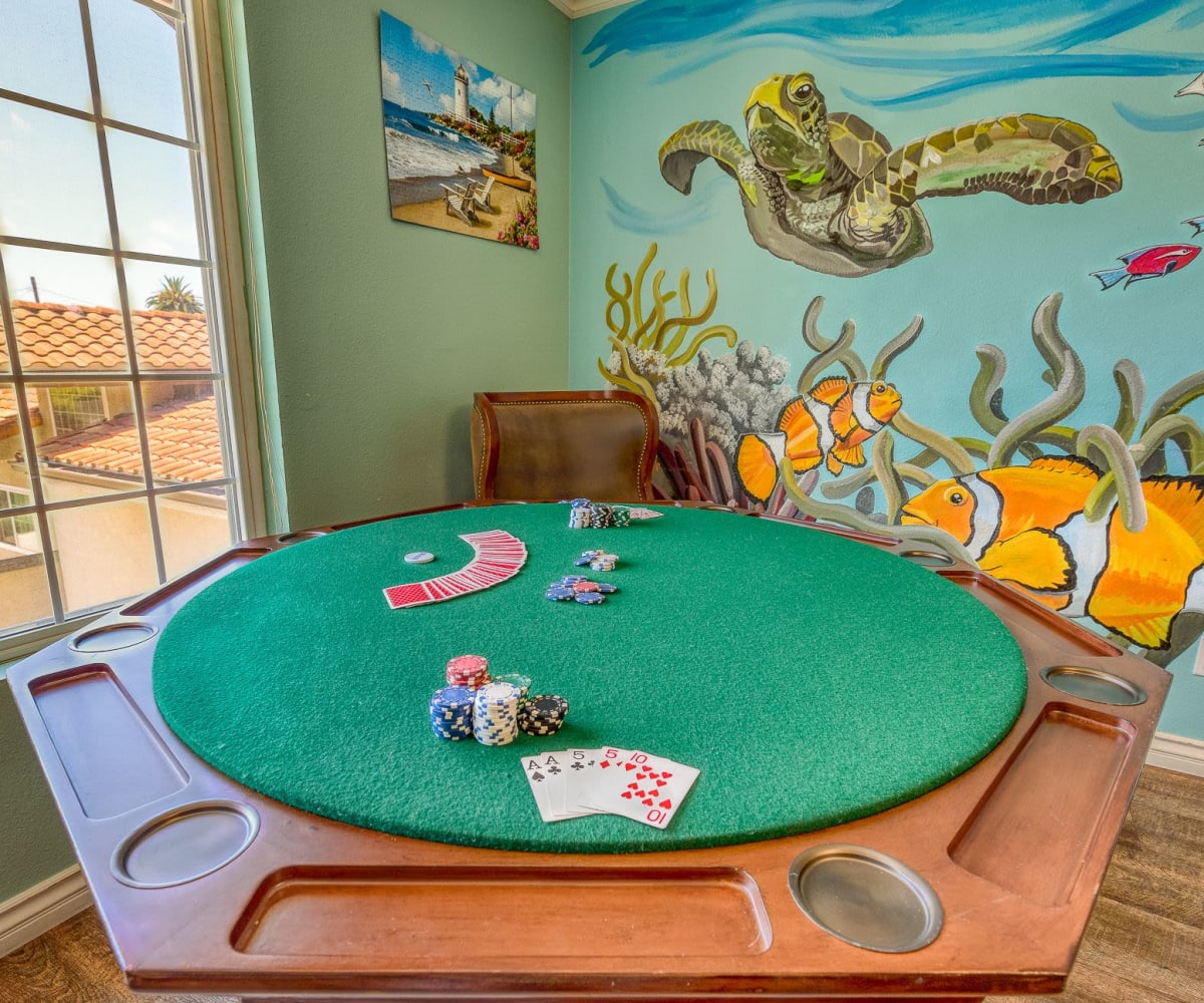 Card table with festive ocean mural on the wall at Pacifica Senior Living South Coast in Costa Mesa, California