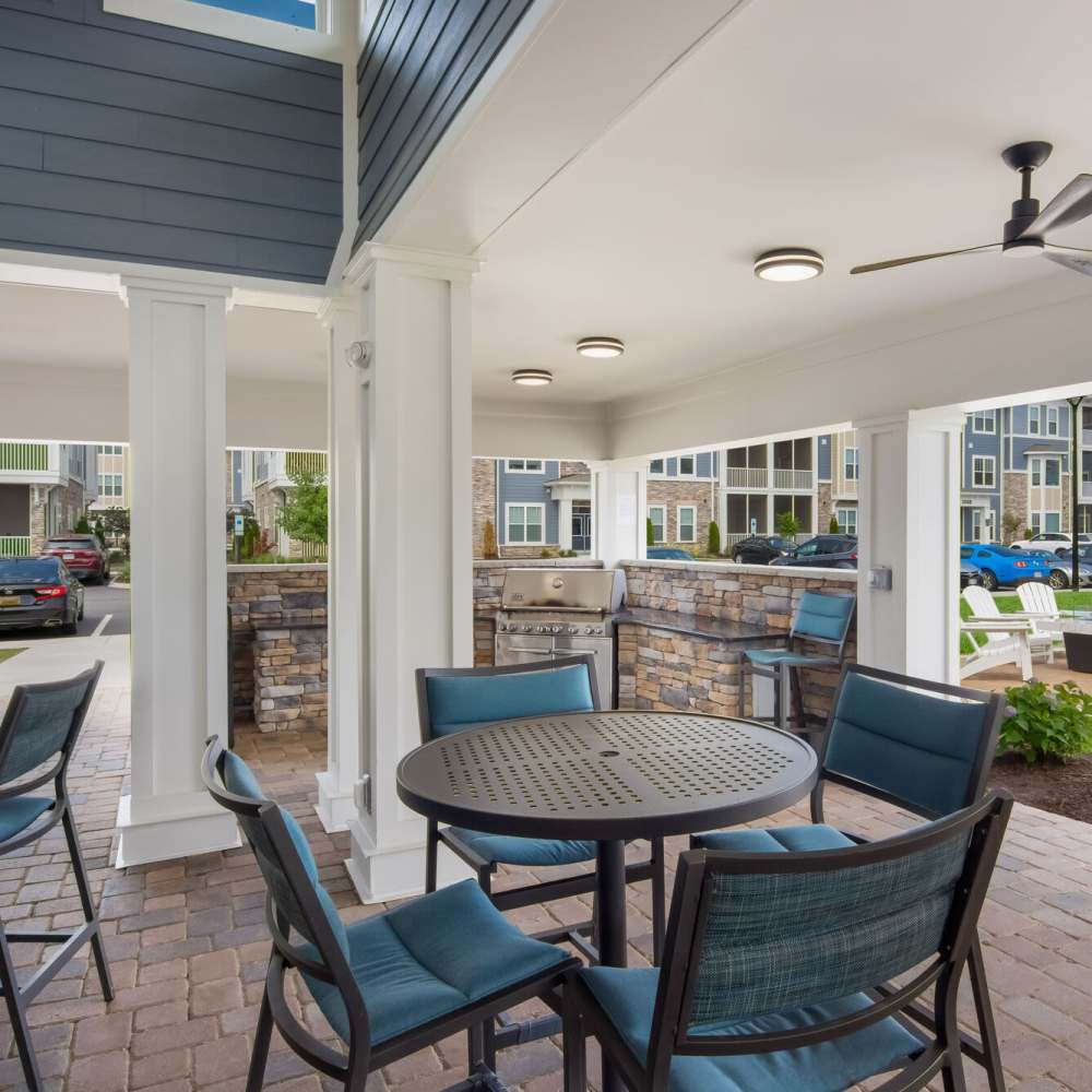 Outdoor grill area with seating and ceiling fan at The Apartments At Kelton Station in Williamsburg, Virginia