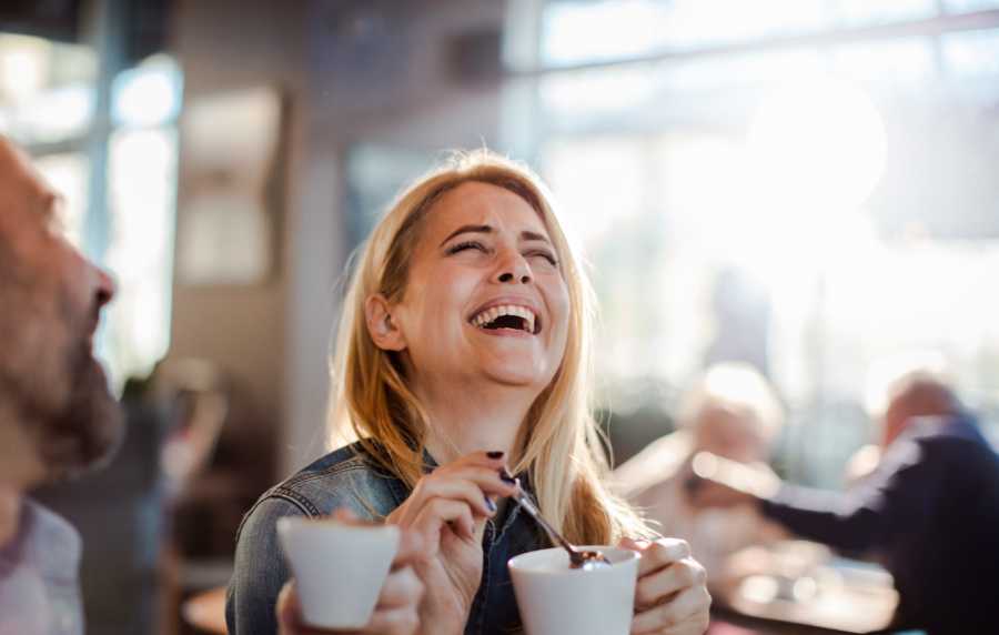 Two friends enjoying coffee at a modern bar table, smiling and chatting in a bright space at Rincon Apartments in McAllen, Texas 