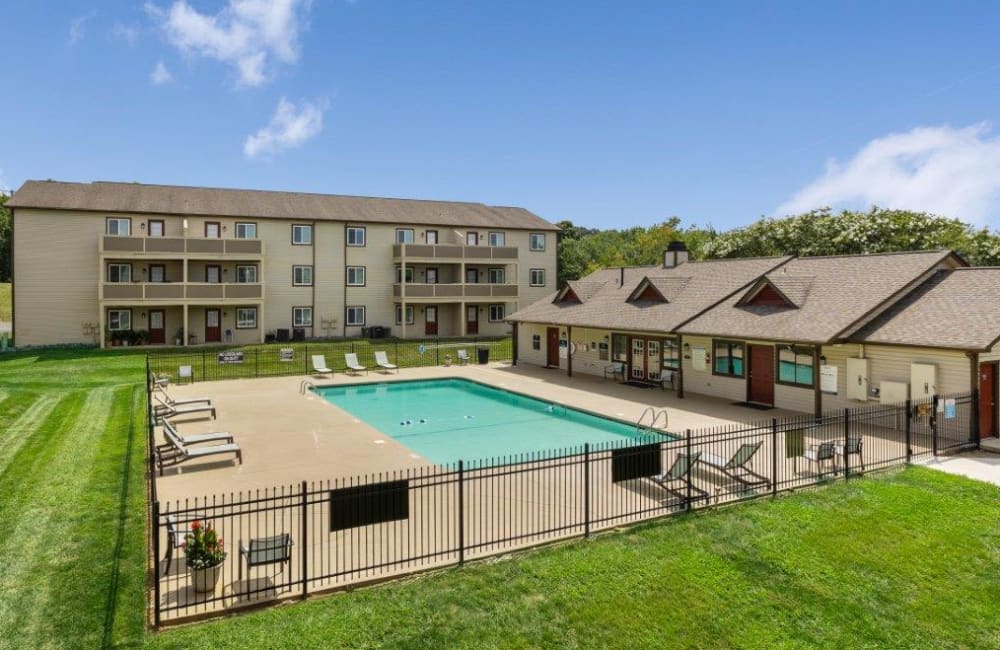 Fenced in swimming pool with lounge chairs through the deck at Gable Oaks Apartment Homes in Rock Hill, South Carolina