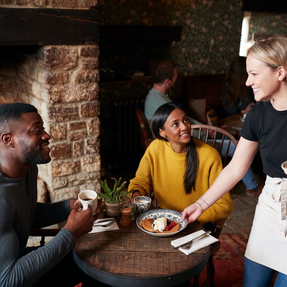 Couple chatting with their server as their food arrives at their favorite café near Oaks Vernon in Edina, Minnesota