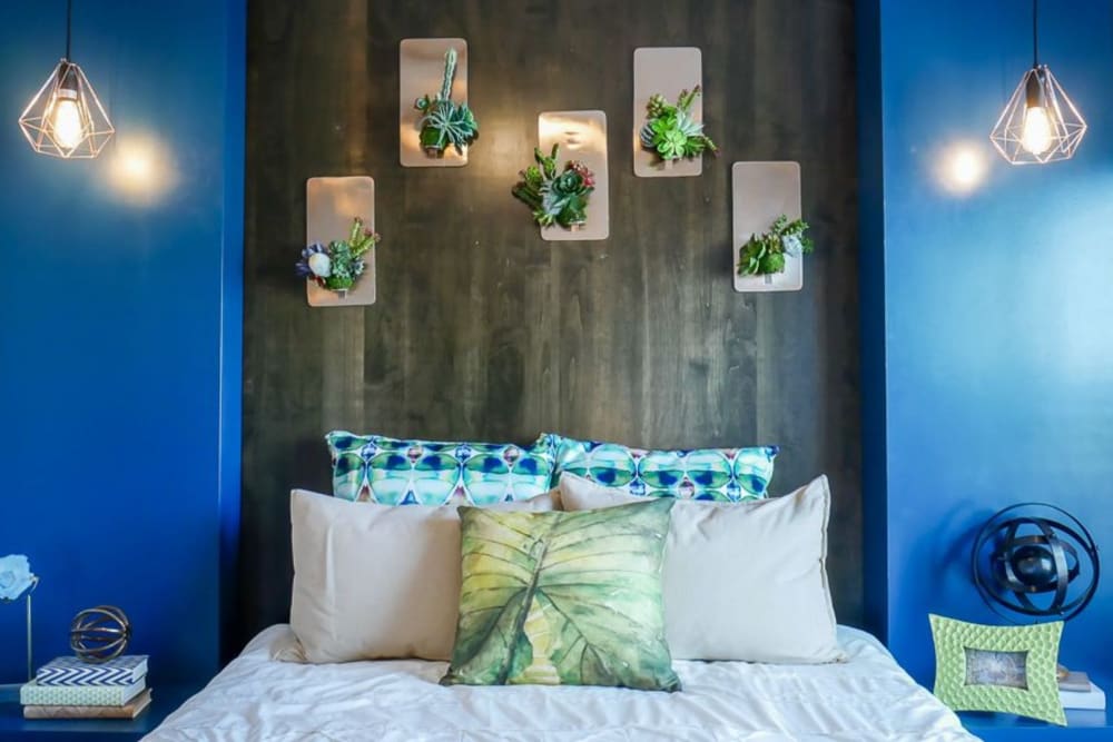 Model bedroom with modern furnishings and blue accent wall at Biltmore at the Park in Pflugerville, Texas