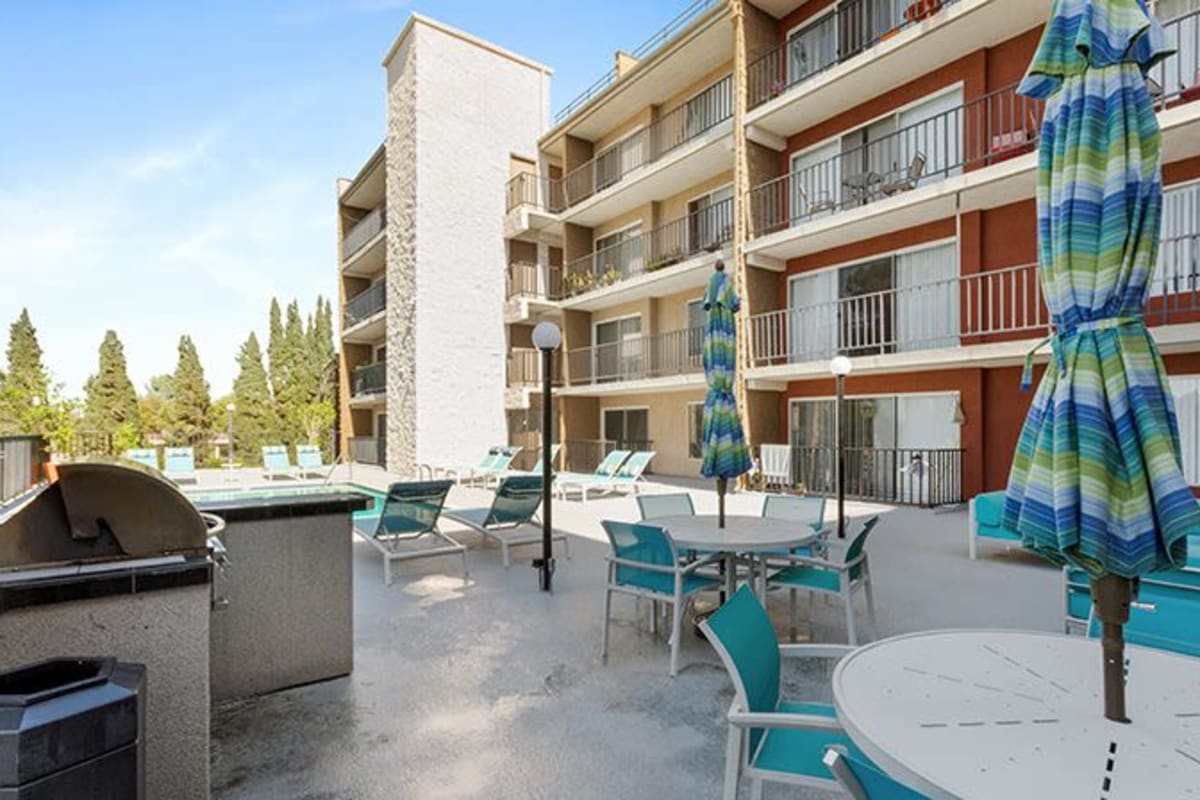 Barbeque area with tables and umbrellas at Amanda Regency Apartments, Van Nuys, California