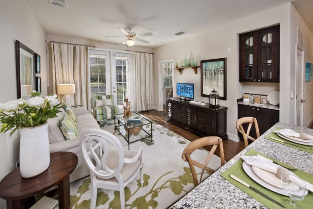 Model living room with wood-style floor and a ceiling fan at Evander Square in Celebration, Florida