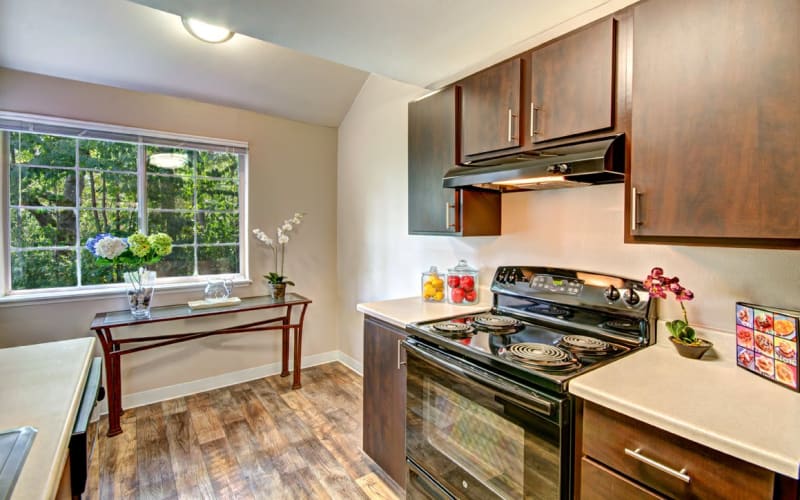 An updated kitchen with brown wood cabinets at Wellington Apartment Homes in Silverdale, Washington