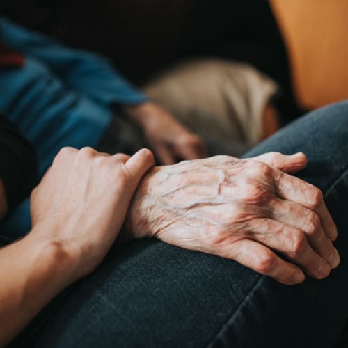 Resident holding hands with a caretaker at Oxford Springs Tulsa Memory Care in Tulsa, Oklahoma