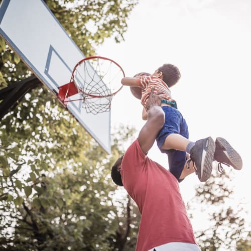 A father holding his son and playing basketball at Lyman Park in Quantico, Virginia