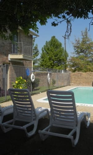 Community pool and shaded lounge seating at Highlands of Grand Prairie in Grand Prairie, Texas