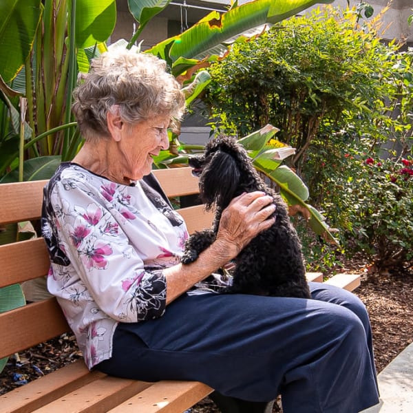 A woman outside with her dog at Serra Highlands Senior Living in Daly City, California