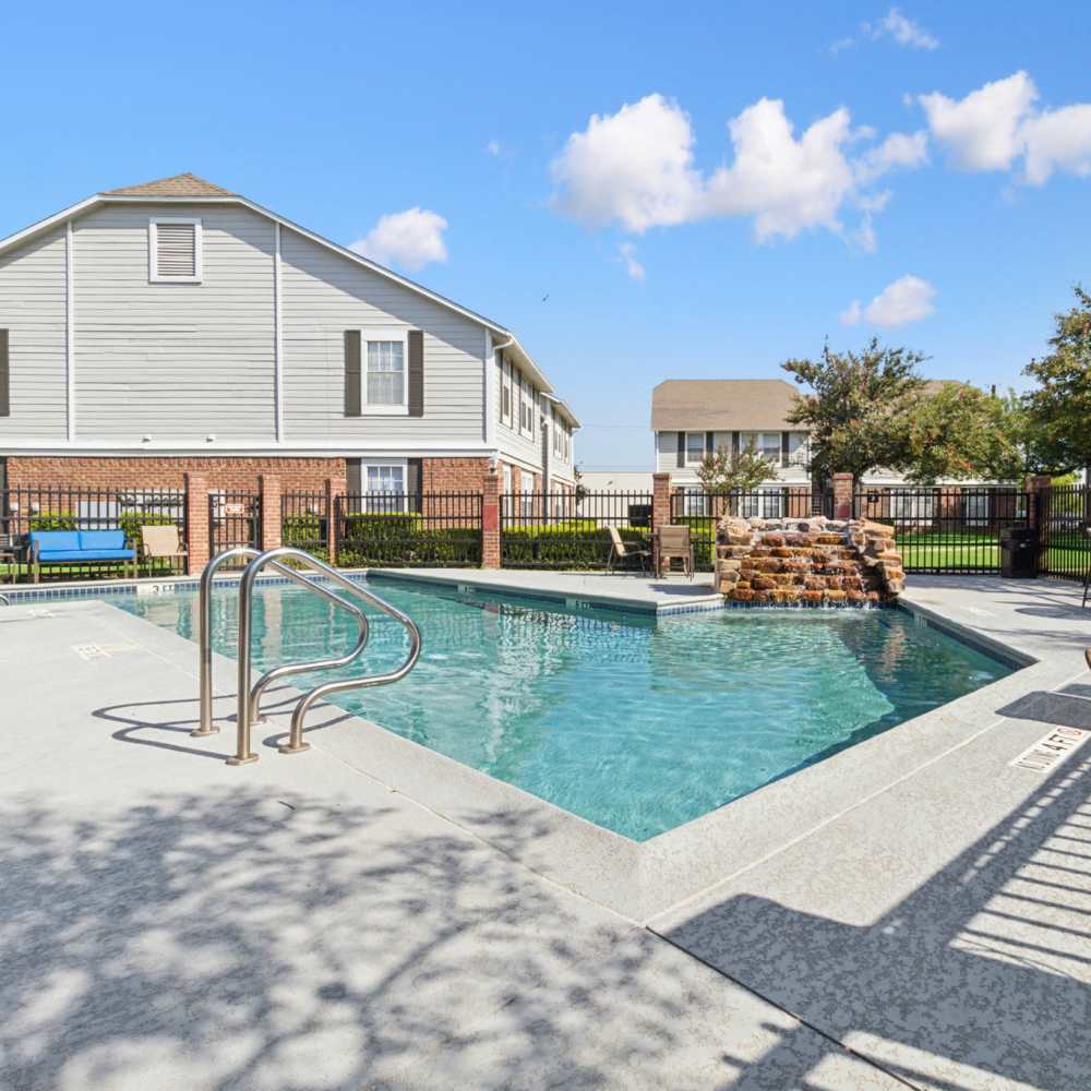 Sparkling pool with lounge chairs at Arbors of Taylor in Taylor, Texas
