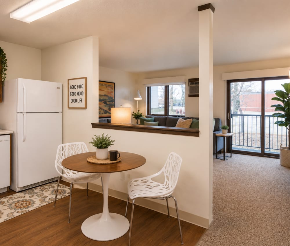 Bright kitchen with white appliances, wood-style flooring, and cozy dining area with round table and chairs at Riverbirch in Ames, Iowa