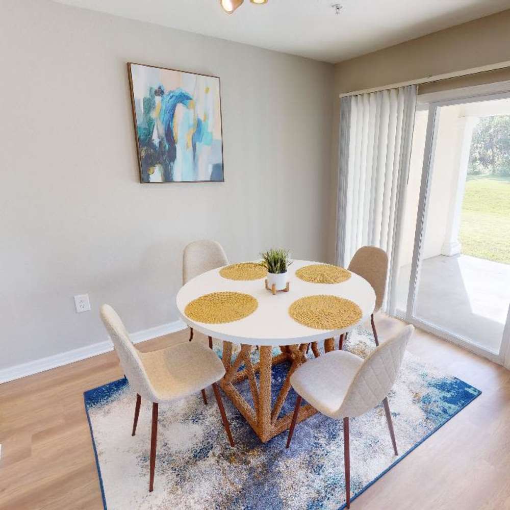 Bright dining area with round table, four chairs, and sliding door to grassy patio at The Reserve at Brookhaven in Palm Coast, Florida