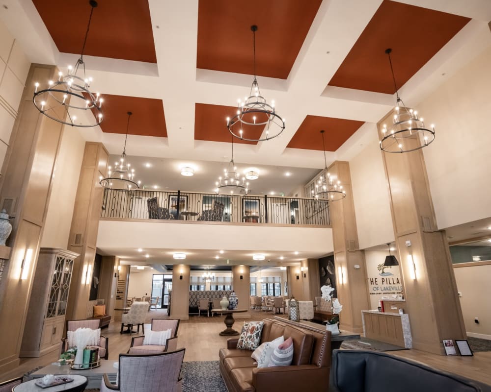 Spacious lobby and reception area with high ceiling and chandeliers at The Pillars of Lakeville in Lakeville, Minnesota