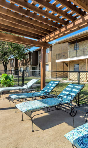 Lounge chairs and swimming pool deck at Franciscan Apartments in Garland, Texas