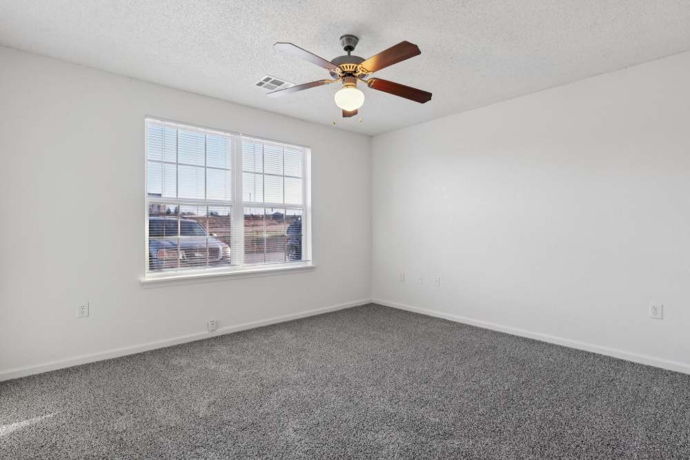 Bright and inviting bedroom featuring plush carpeting and ample natural light at Covington Woods Apartments in Lansing, Kansas.