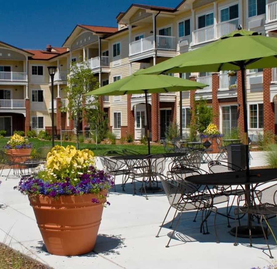 Umbrella covered tables and chairs in an outdoor courtyard at Lakeview Senior Living in Lakewood, Colorado