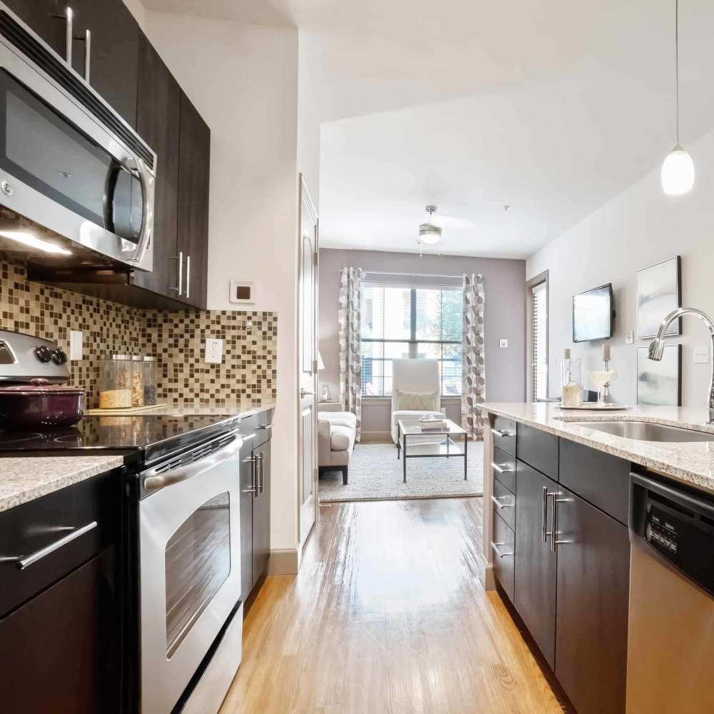 Apartment kitchen with wood-style flooring and dark cabinetry at Grapevine Station in Grapevine,Texas