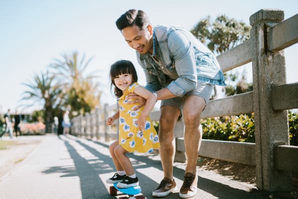 A father helping his daughter skateboard near Mode at Owings Mills in Owings Mills, Maryland