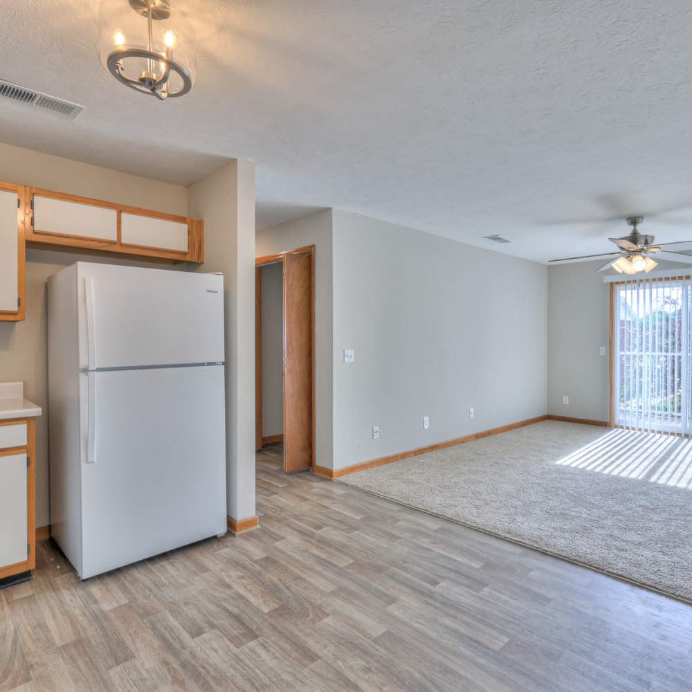 Spacious living room with wood-style flooring and kitchen with refrigerator at Laurel Wood Apartments in Smyrna,Tennessee