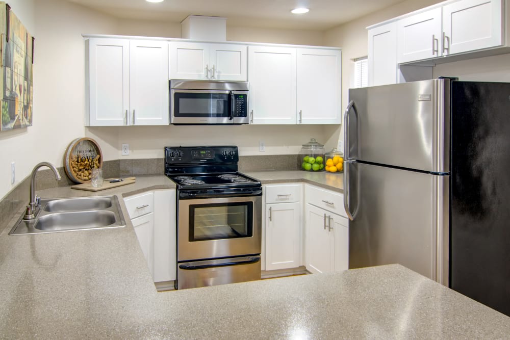 Kitchen with stainless steel appliances and white cabinetry at The Addison Apartments in Vancouver, Washington