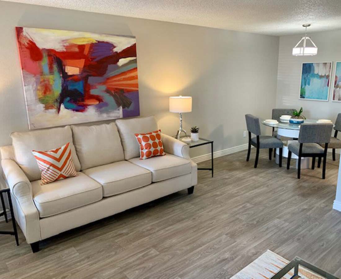 Stylish living room with comfortable couch, wall painting and access to dining room at 544 Southern Apartments in Mesa, Arizona
