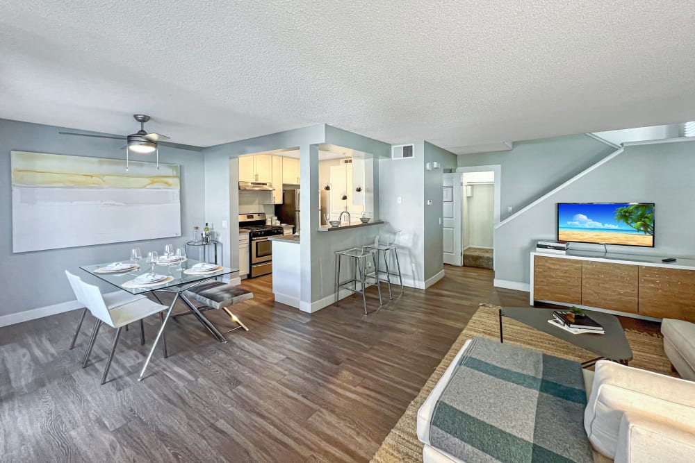 A townhome dining room, living room, and kitchen with wood-style flooring at Portofino Townhomes in Wilmington, California