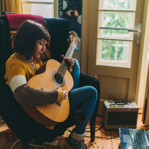 Student recording some acoustic guitar in the comfort of her bedroom at IDENTITY Logan Park in Berkeley, California