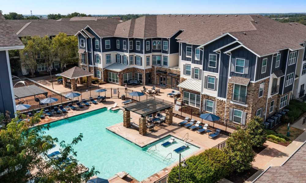 Outdoor swimming pool with lounge chairs beside a multi-story apartment building at The Den in Columbia, Missouri