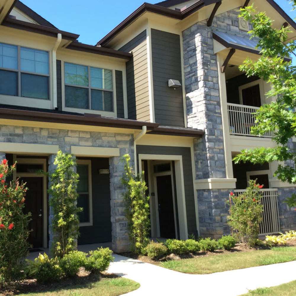 Gated entrance with landscaped pathways and stone accents on apartment building exterior at Plantation Park Apartments in Lake Jackson, Texas