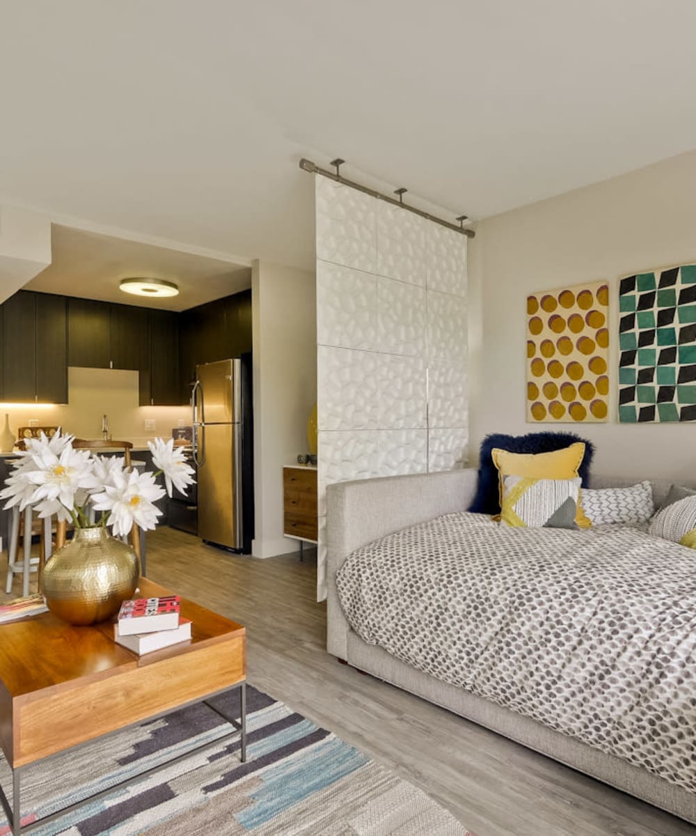 Bedroom and living areas with the kitchen in the background in an open-concept model studio home at Mia in Palo Alto, California