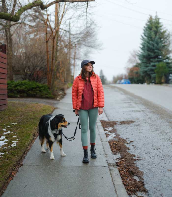 Woman walking dog on a rainy sidewalk at Countryshire Estates in Rochester, New York