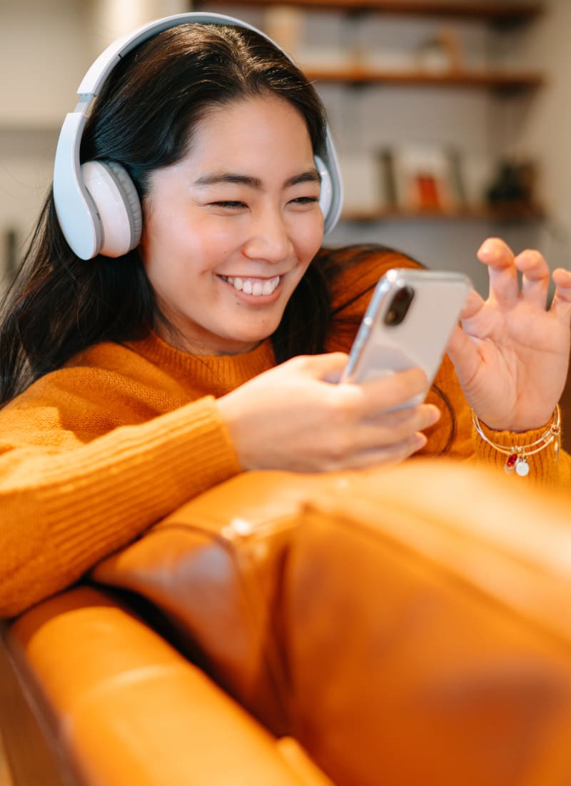 Resident on smartphone with headphones on at Marquis at Treetops in Austin, Texas