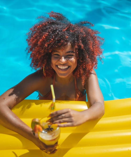 Resident on pineapple floatie in pool at The Avenue at Carlsbad, Carlsbad, California 