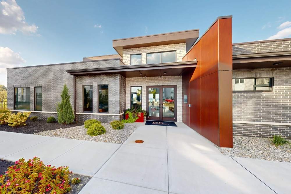 Exterior view of the modern clubhouse at Elevation 800 featuring brick and metal accents, large windows, landscaped walkways, and inviting front entrance.