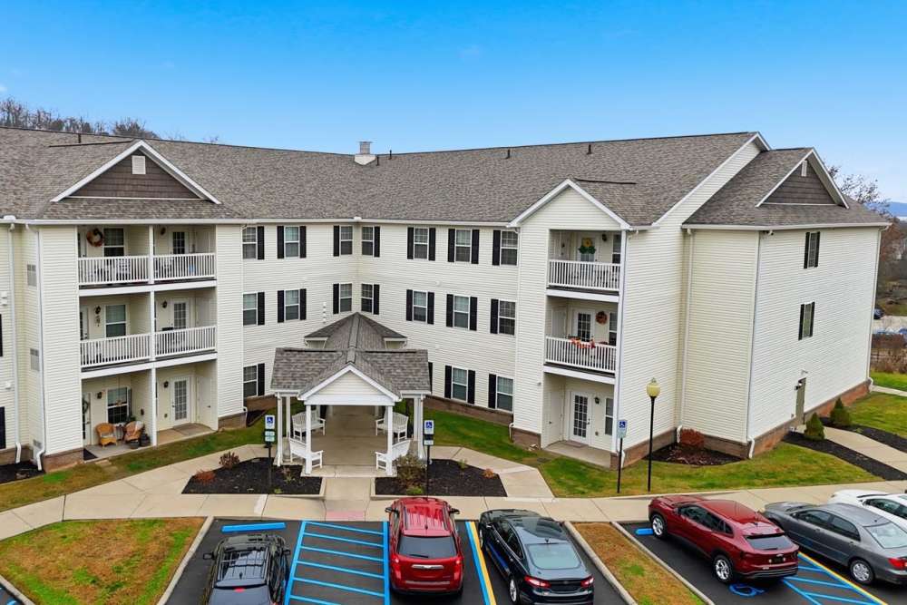 Three-story apartment building with balconies, landscaped entrance, and parking lot at Norwood Greene Senior Living in Marietta, Ohio